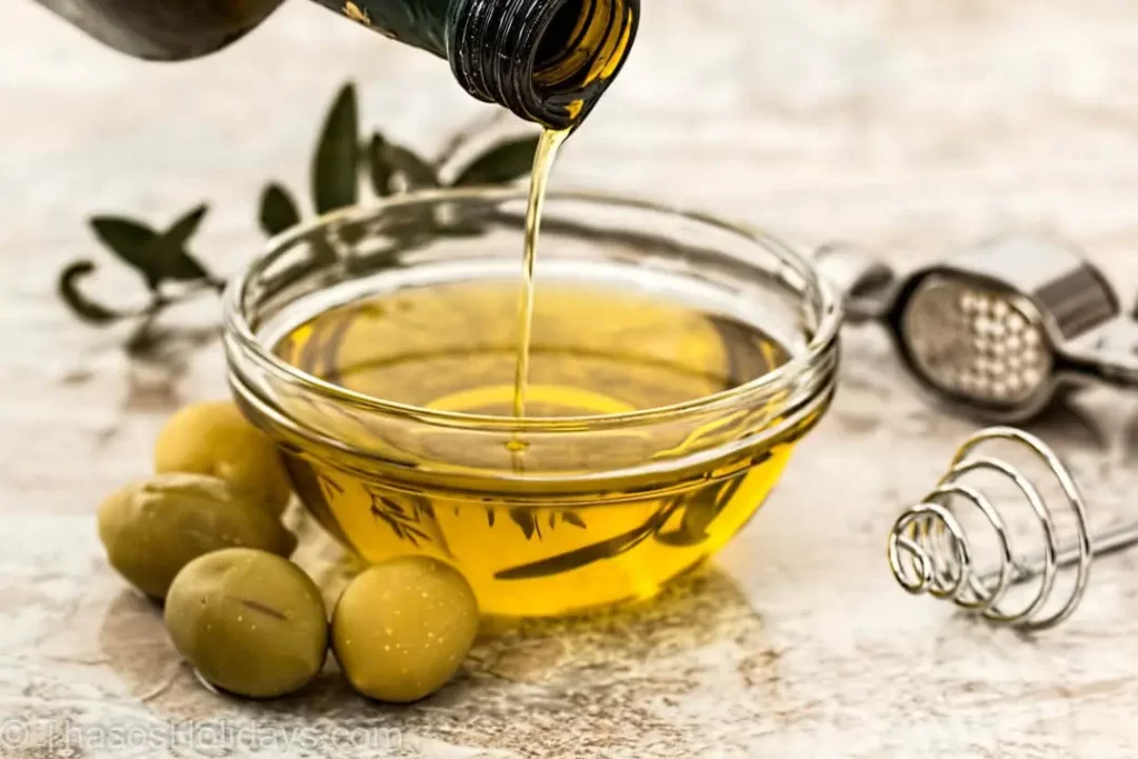 Olive Oil in a bowl while a hand is taking some honey out