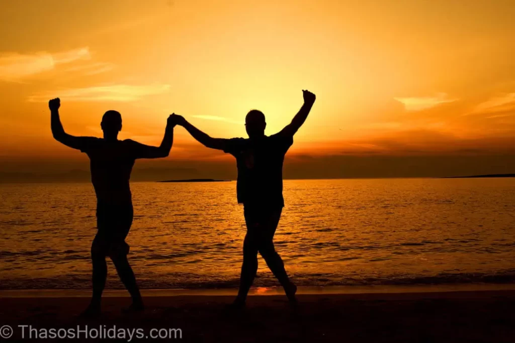 facts about Thassos Two people greek dancing on a beach during sunset